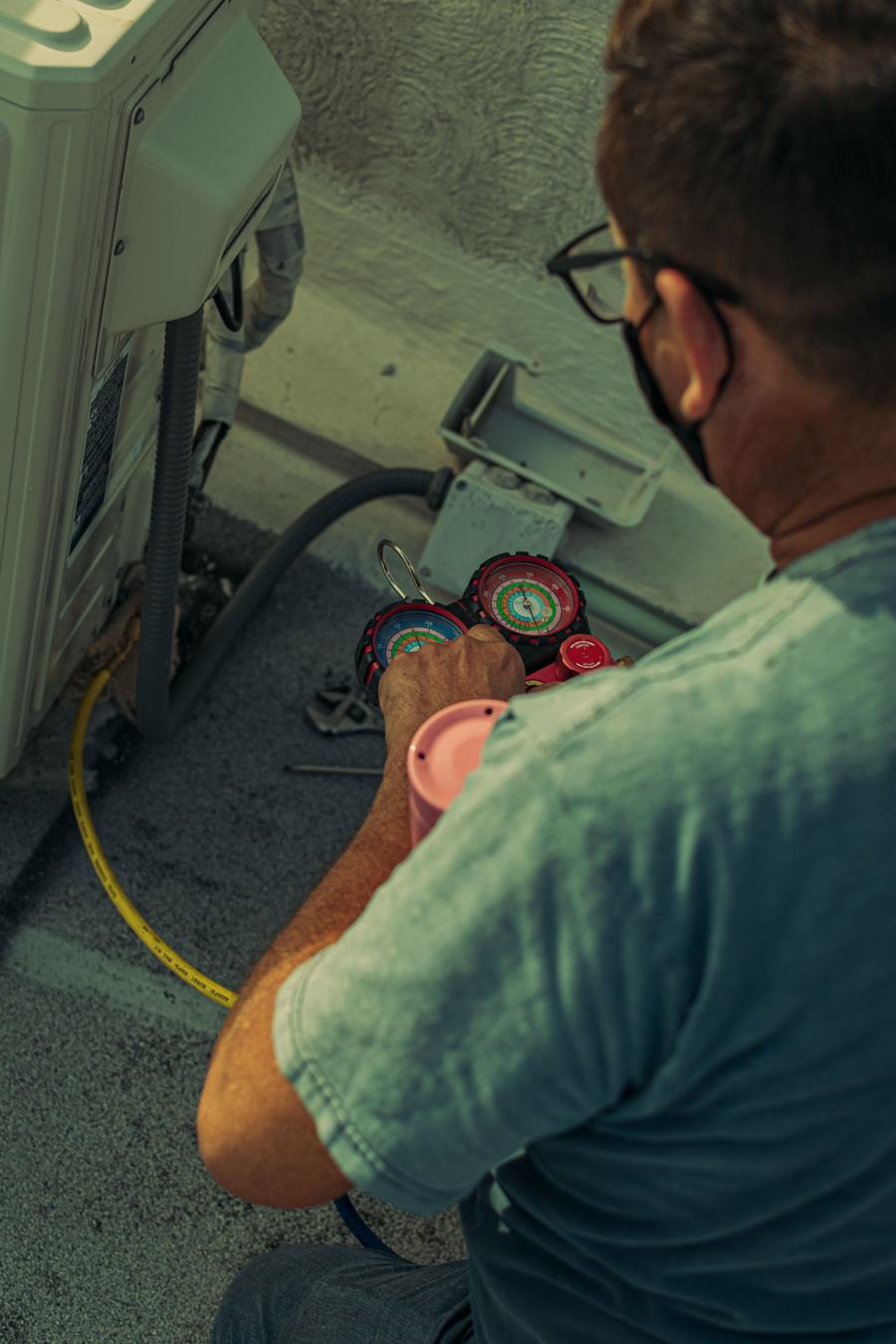 Technician reading refrigerant gauges hooked to an outdoor unit