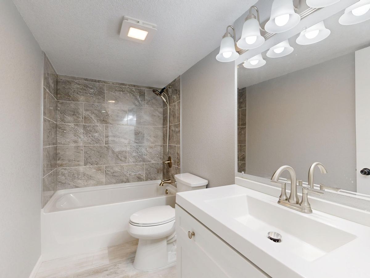 Remodeled bathroom with a new tub, tile surround, toilet and brushed-nickel faucet