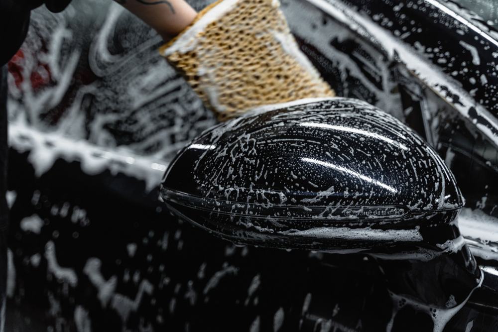 Wash mitt and thick foam on a black car's mirror