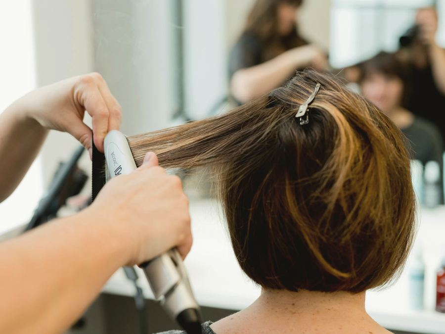 Stylist smoothing a chin-length bob with warm highlights
