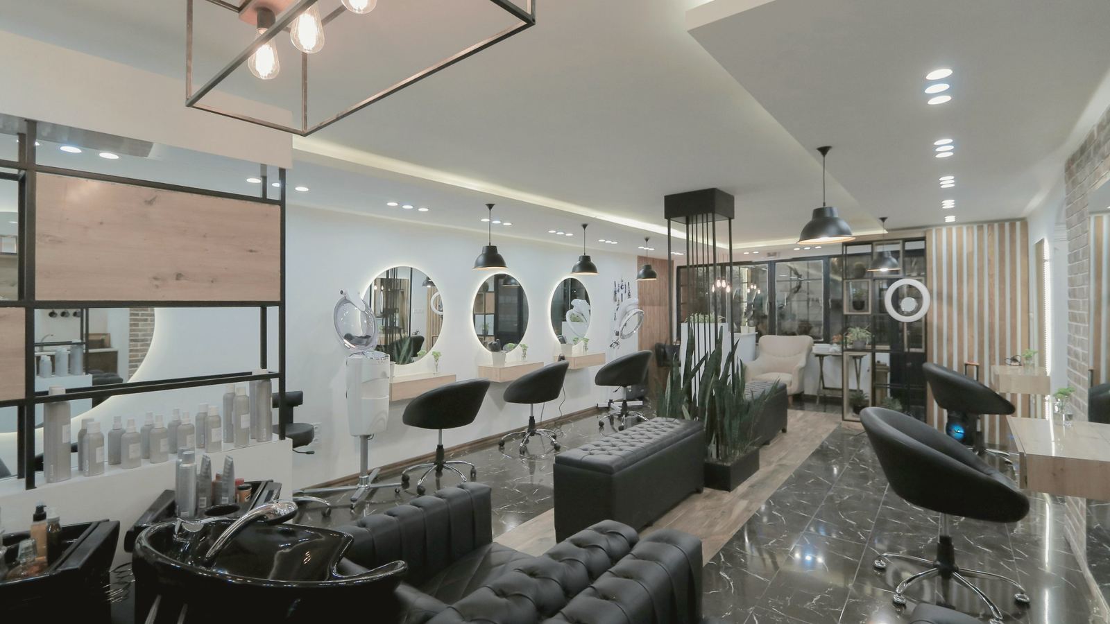 Inside the salon: round lit mirrors, black styling chairs and wash stations