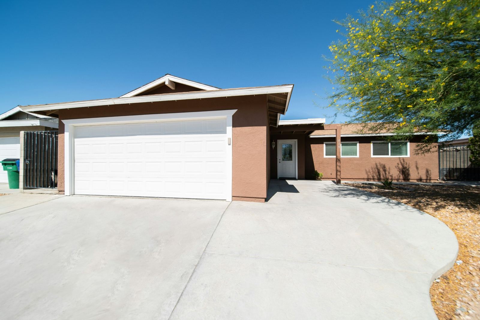 New light-gray driveway with a curved edge in front of a single-story stucco home