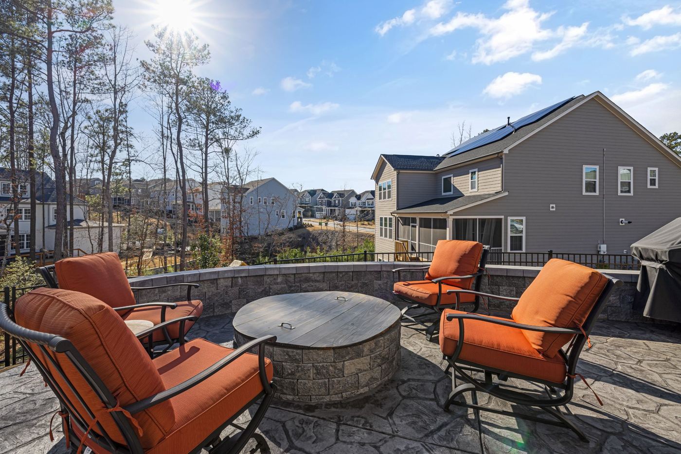 Stamped stone-pattern patio with a round fire pit and orange patio chairs