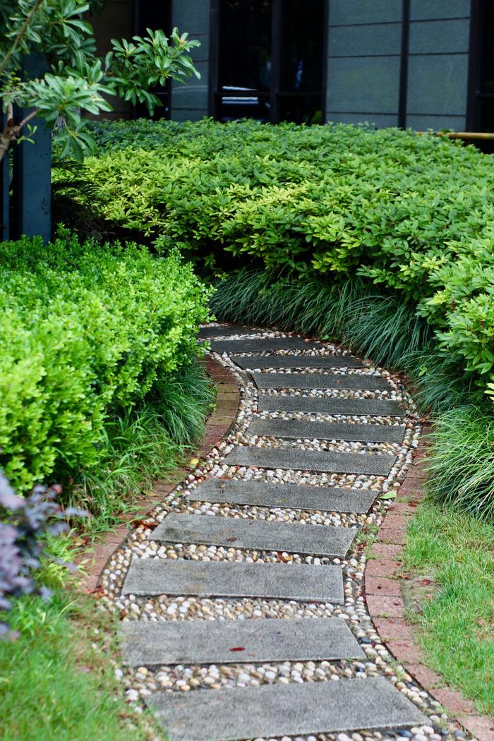 Curved front walk of concrete steppers set in river rock