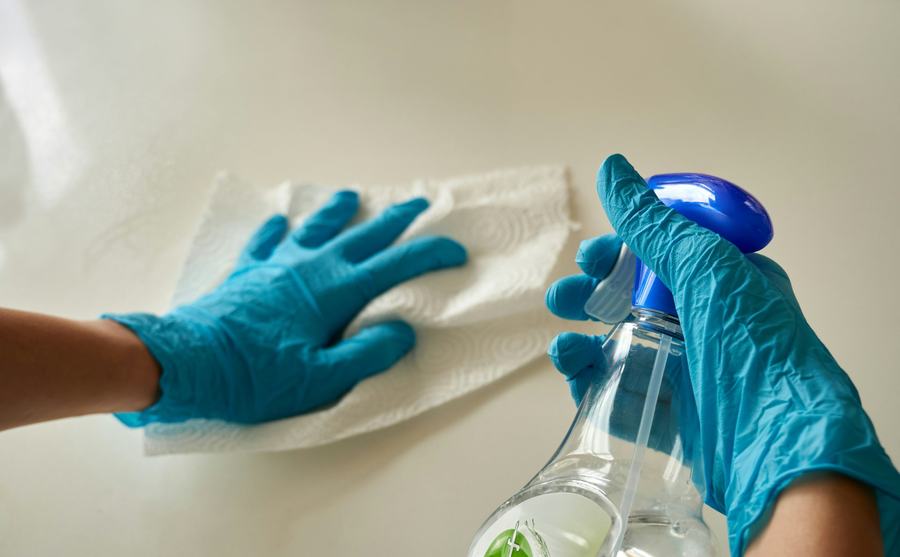 Gloved hands spraying and wiping a counter