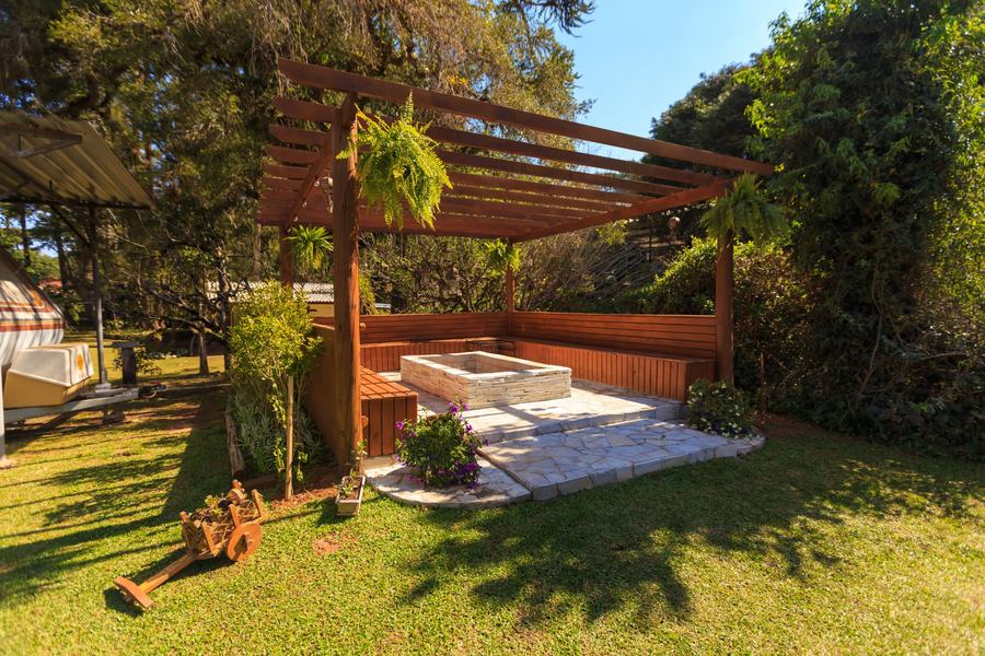 Stained wood pergola over built-in benches and a stone patio