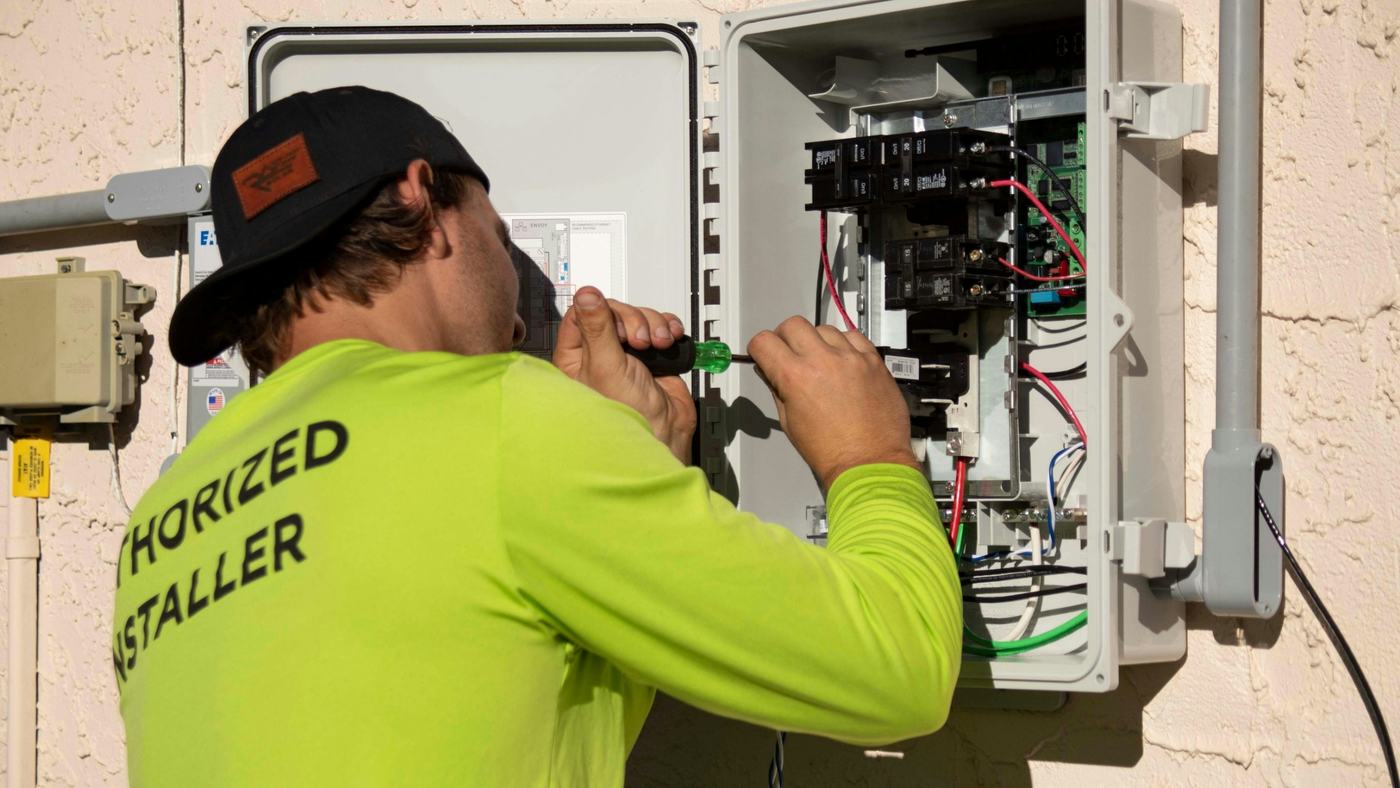 Electrician tightening a breaker in an open outdoor panel