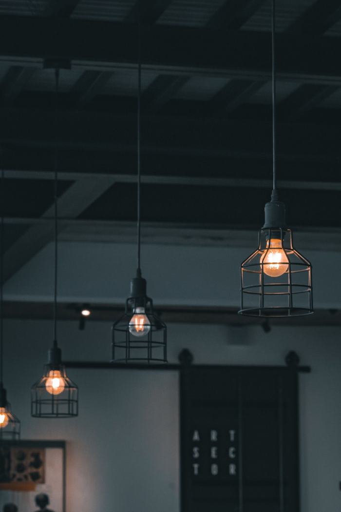 Caged pendant lights with warm bulbs hanging from a dark ceiling